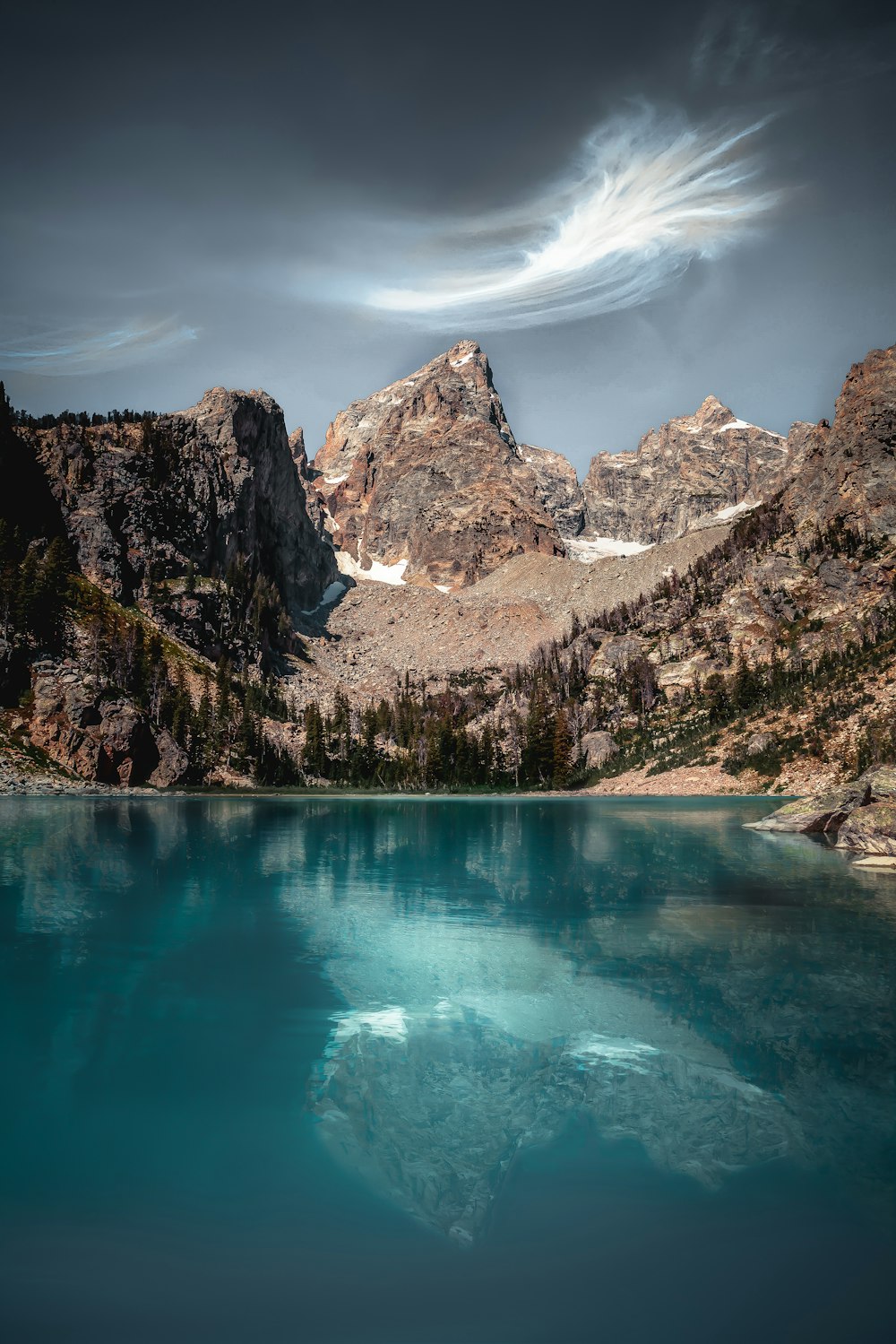 blue lake surrounded by brown and white mountains under blue sky during daytime