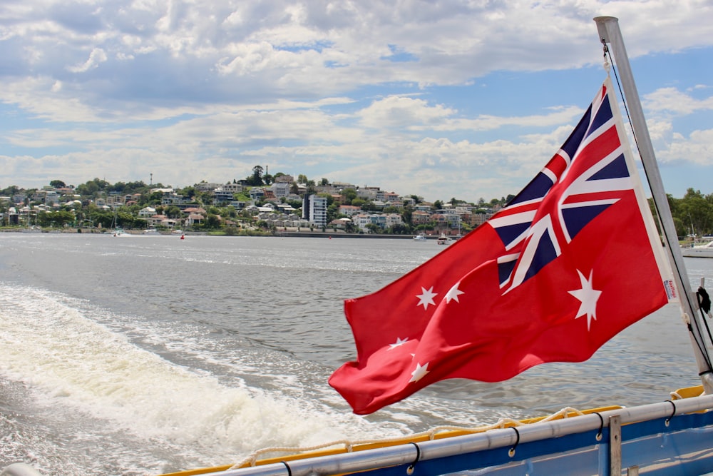 red flag on brown wooden boat on sea shore during daytime