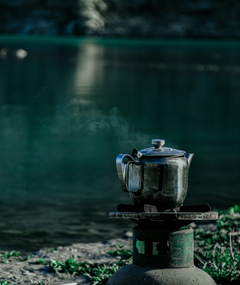 black and gray kettle on black metal stand near body of water during daytime