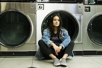 woman in blue denim jacket sitting on front load washing machine