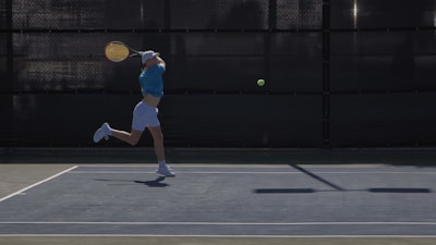 Side view of a player executing a backhand with handrills equipment in motion.