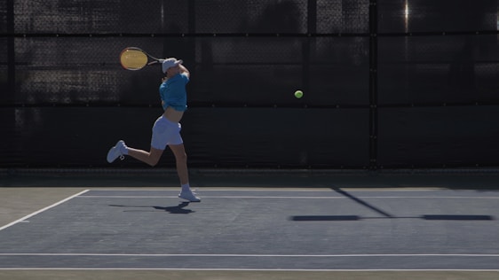A vibrant action shot of a tennis player wearing AceCourtsz apparel, mid-swing on a sunlit court.