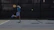 A smiling tennis coach demonstrating a backhand stroke on a sunny court.