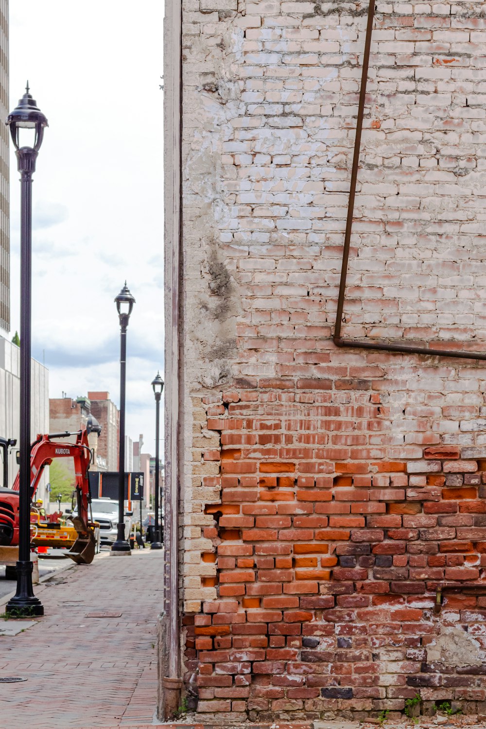 red car parked beside brown brick wall during daytime