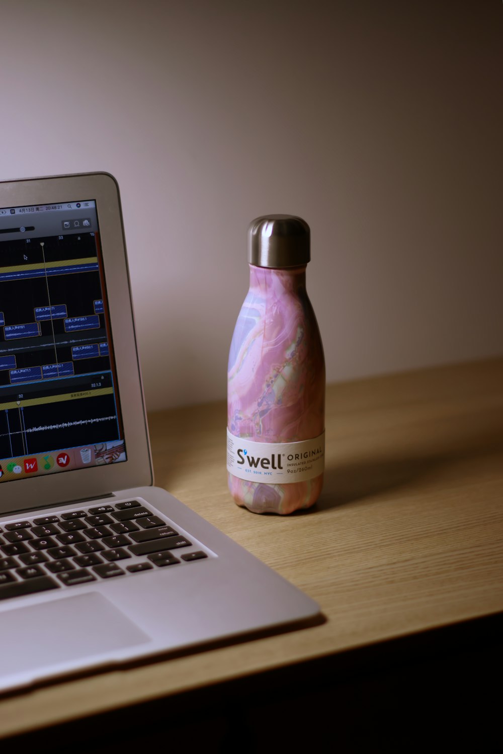 purple and white plastic bottle beside macbook pro