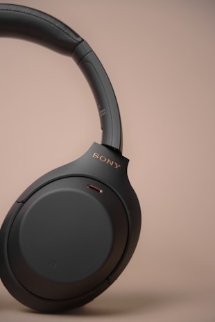 Close-up of a sleek premium wireless headphone with rose gold accents on a black minimalist background.