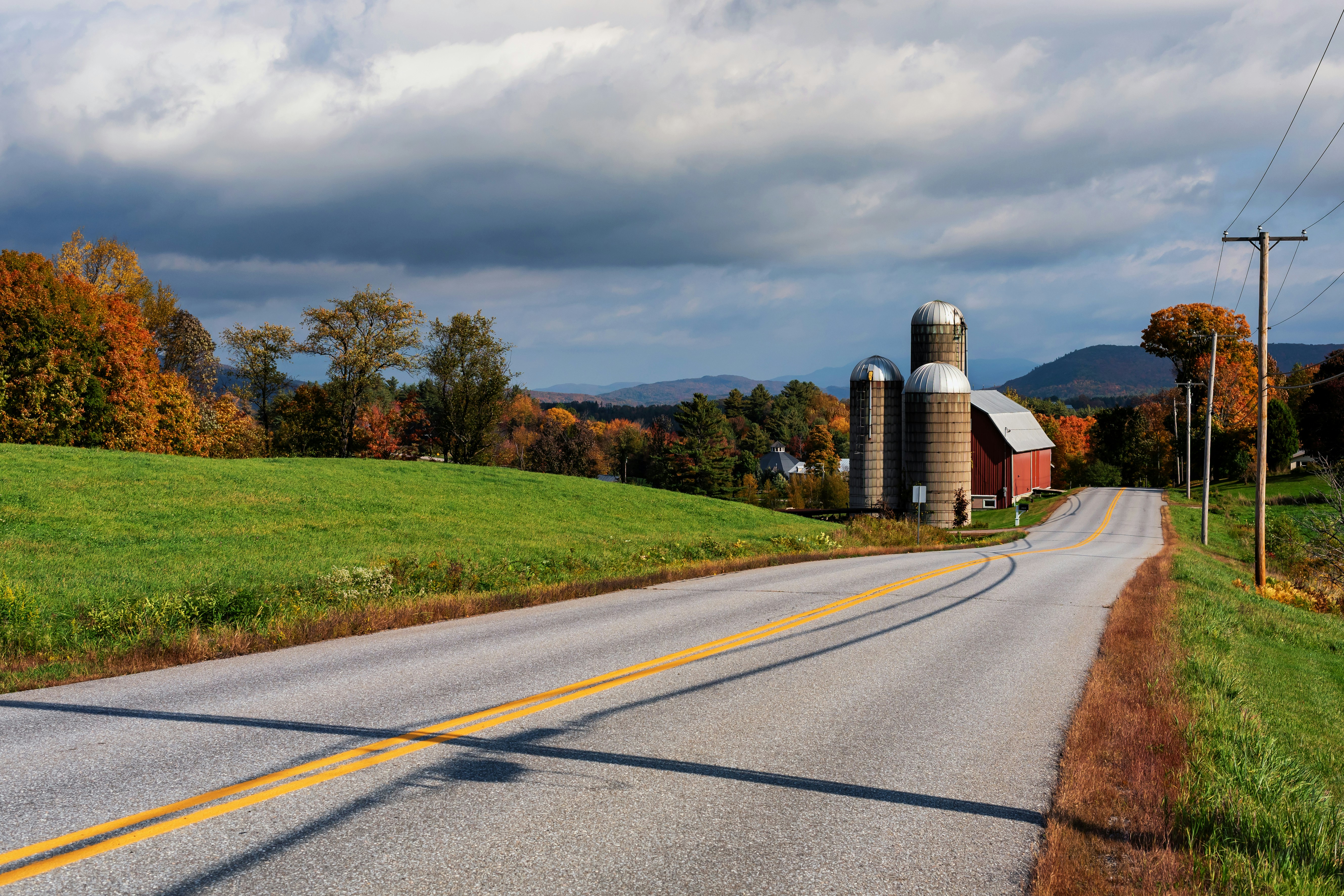 Rural road leads to a farm with silos and silos.