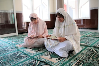 woman in white hijab sitting on green and white rug