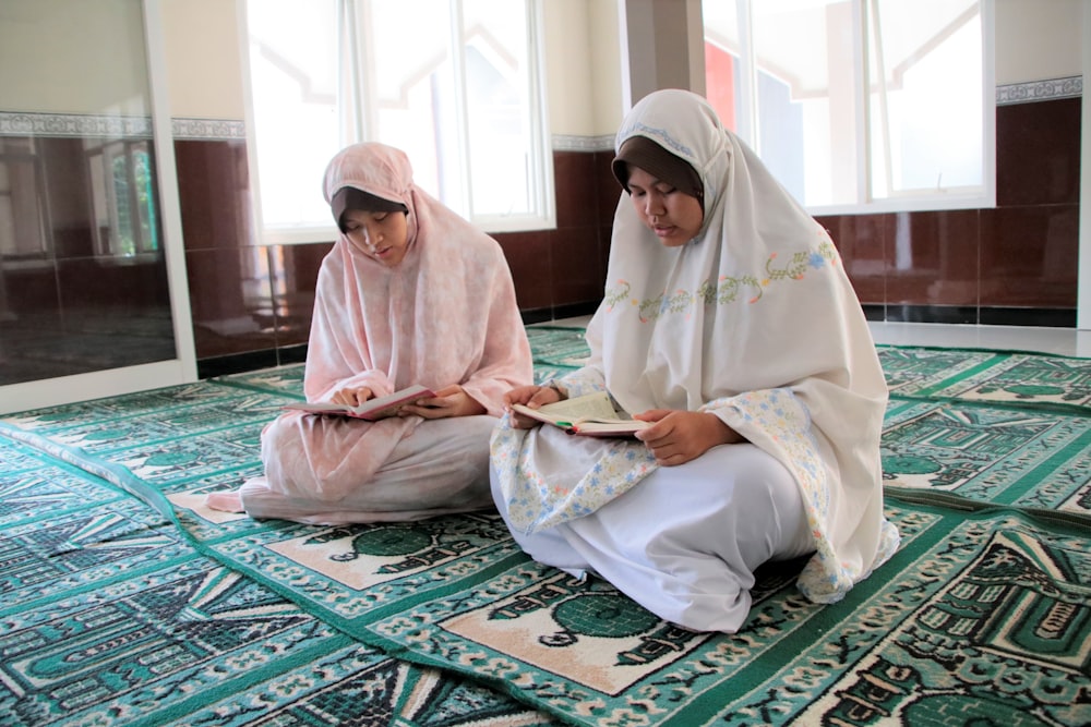 woman in white hijab sitting on green and white rug