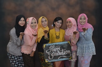 3 women wearing hijab standing beside black and white wall