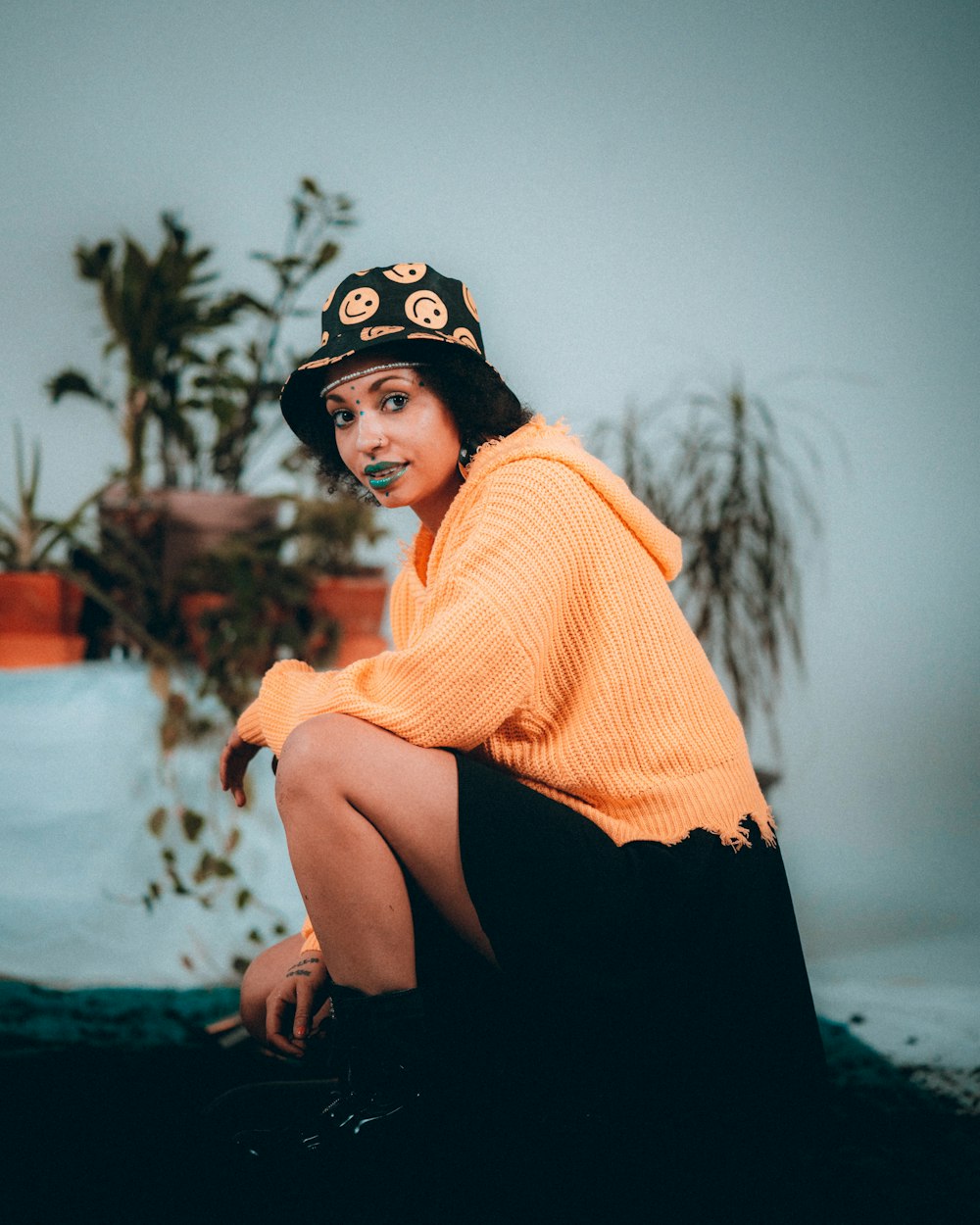 woman in orange knit sweater and black skirt sitting on ground