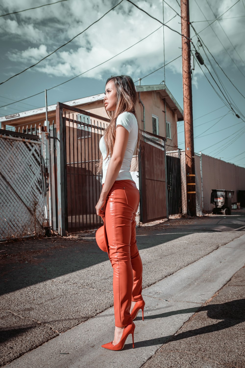 woman in white shirt and red pants standing on sidewalk during daytime