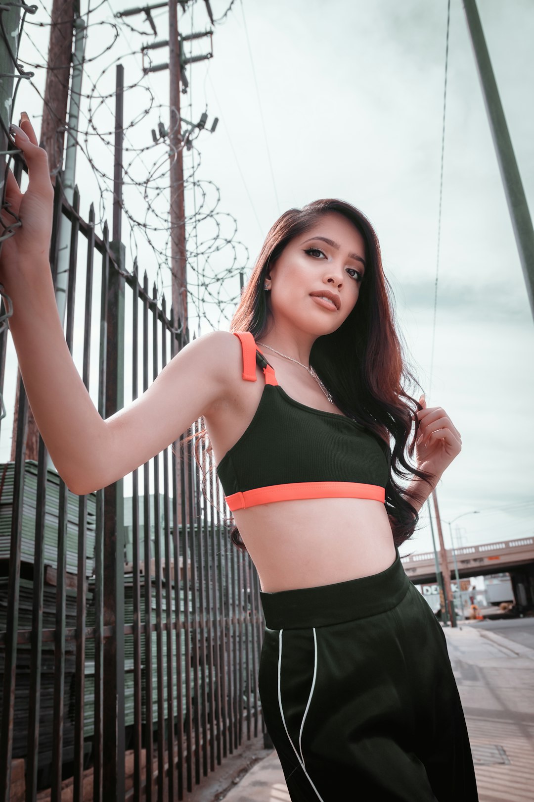 woman in red sports bra and black shorts standing near black metal fence during daytime