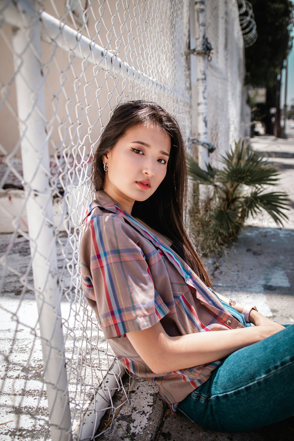 woman in red and blue plaid shirt and blue denim jeans sitting on concrete floor