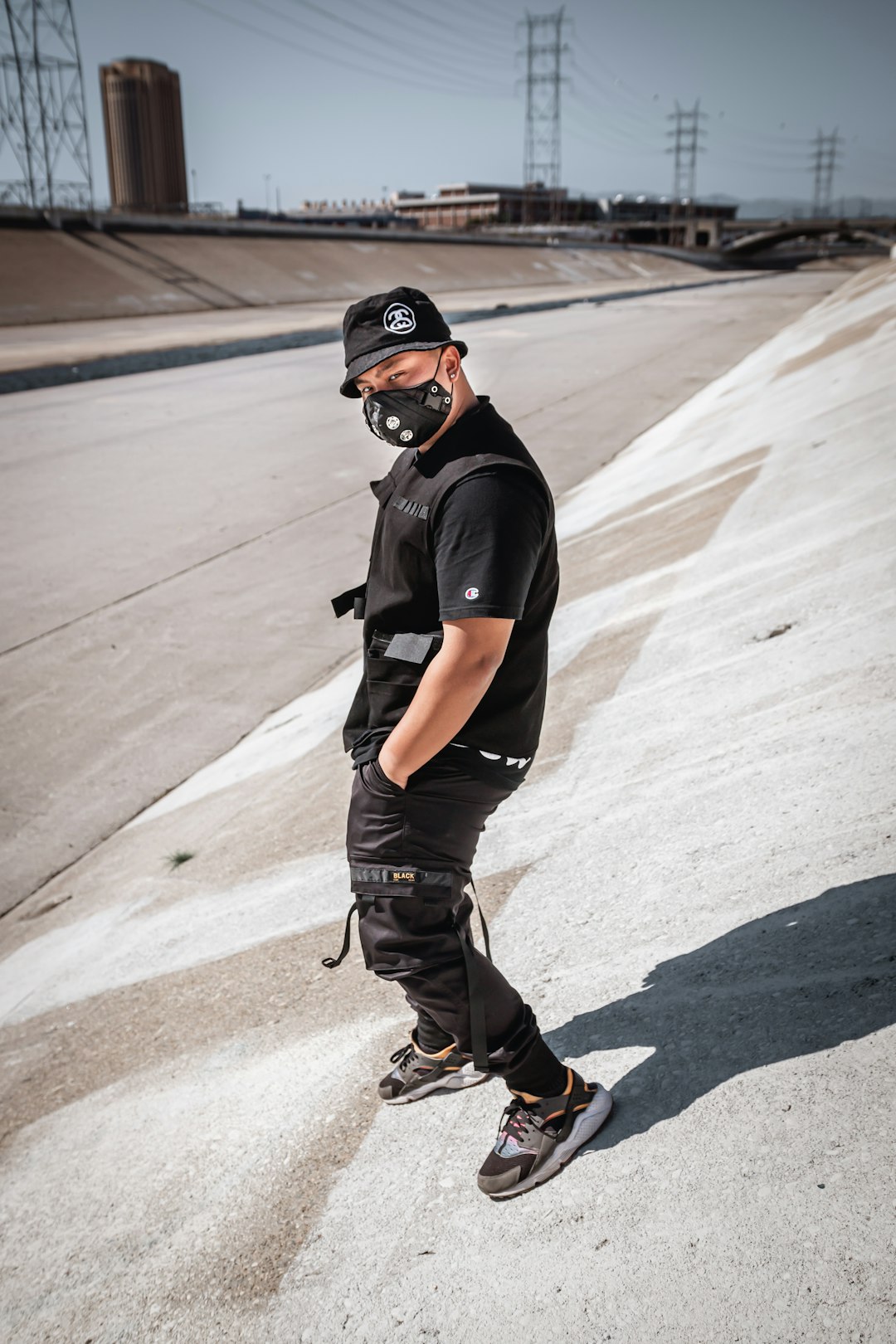 man in black t-shirt and gray denim jeans wearing black helmet standing on gray asphalt