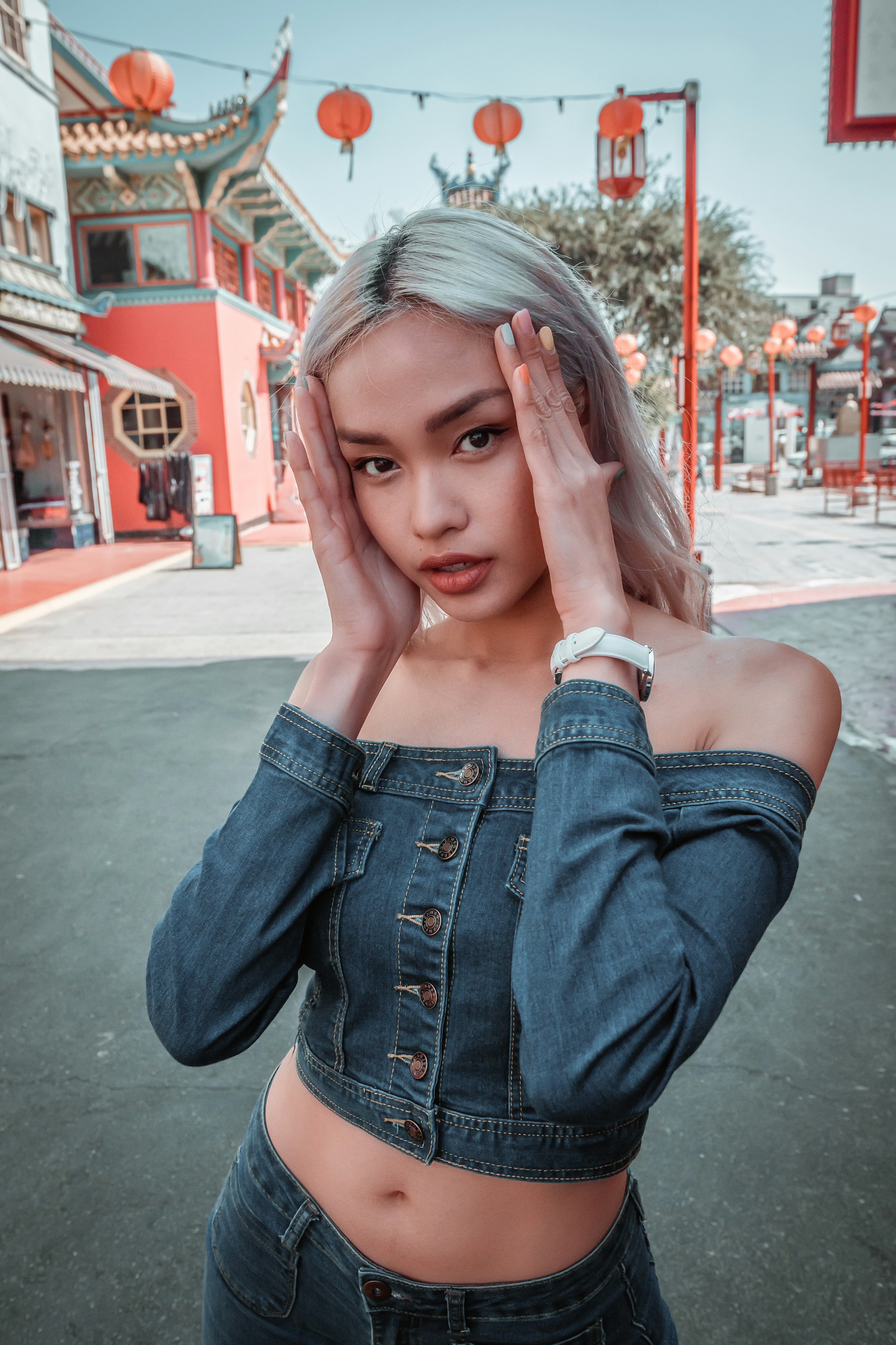 woman in blue denim jacket covering her face with her hand