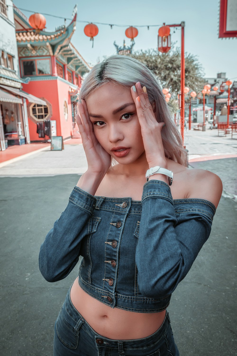 woman in blue denim jacket covering her face with her hand