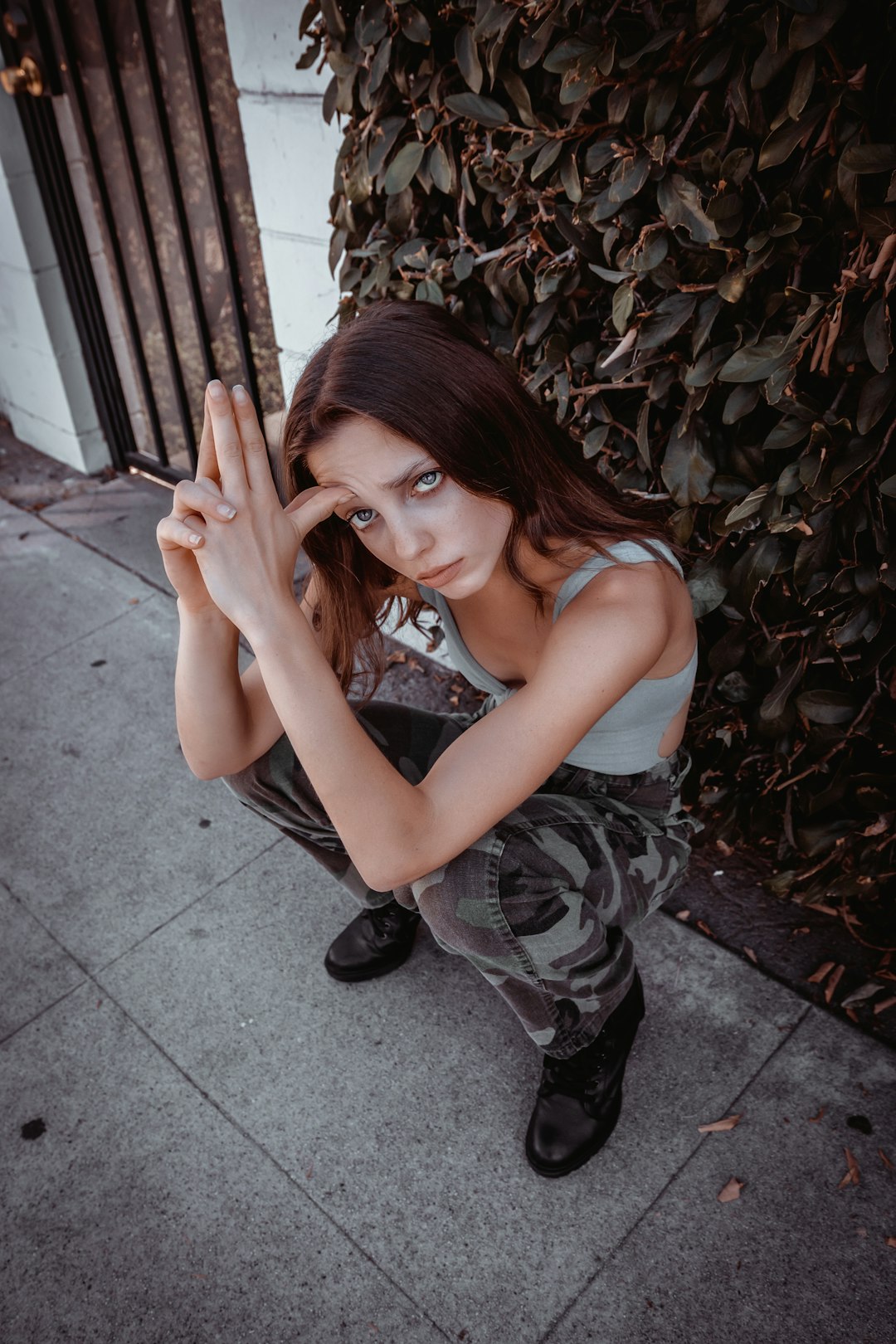 woman in gray tank top and black and white camouflage pants sitting on gray concrete floor