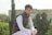 man in black vest and white dress shirt sitting on green grass field during daytime