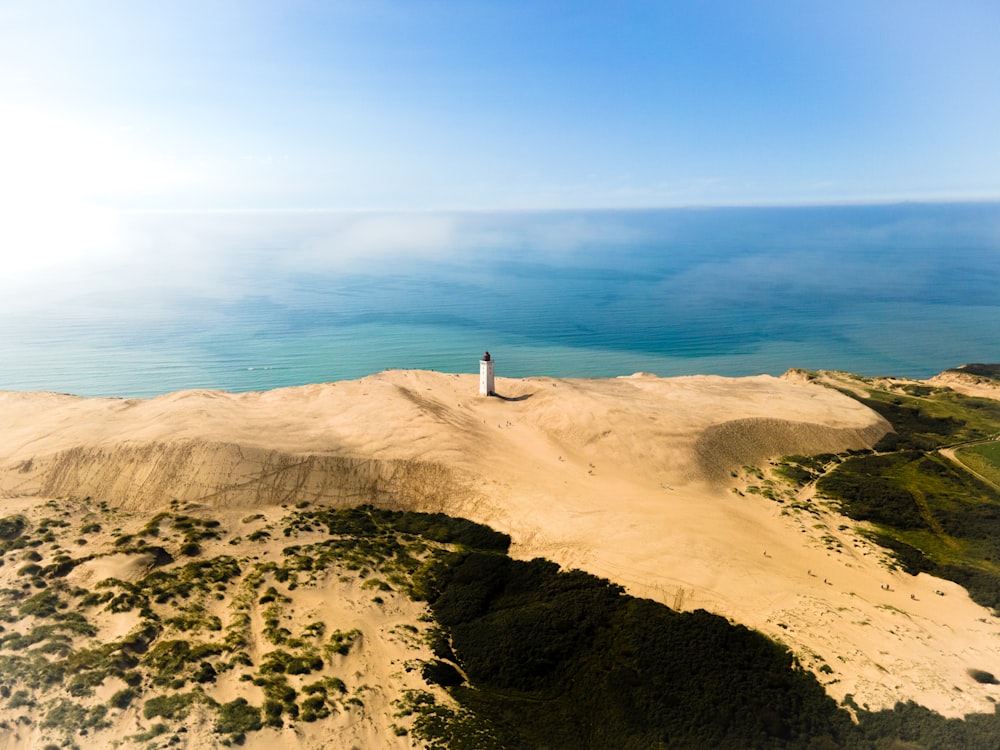 Person, die tagsüber auf braunem Sand in der Nähe von Gewässern steht