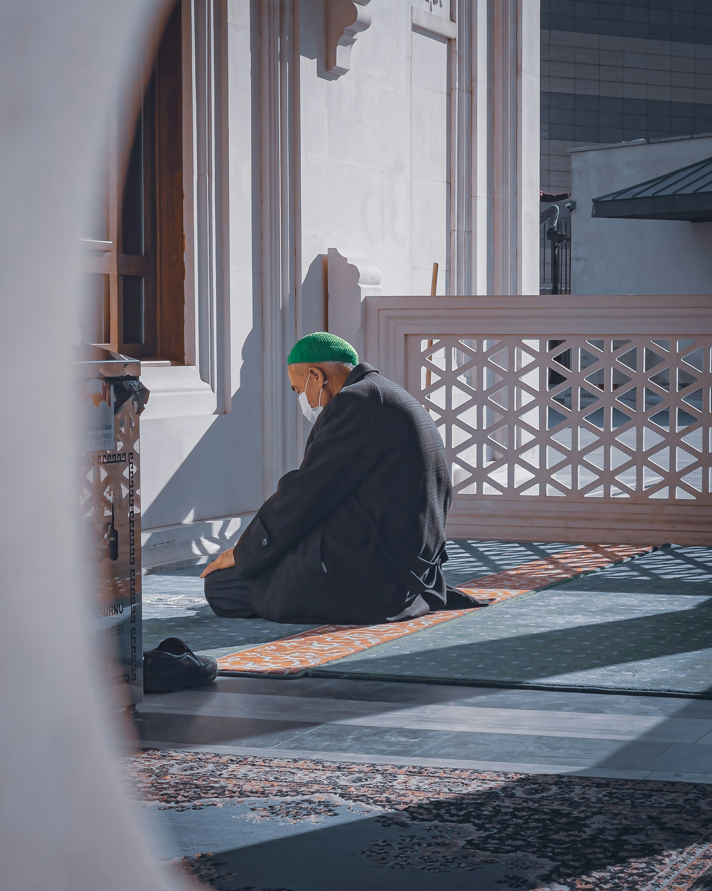 An old muslim man worshiping his god and praying afternoon at the door of the mosque on a Sunday day of Ramadan 
