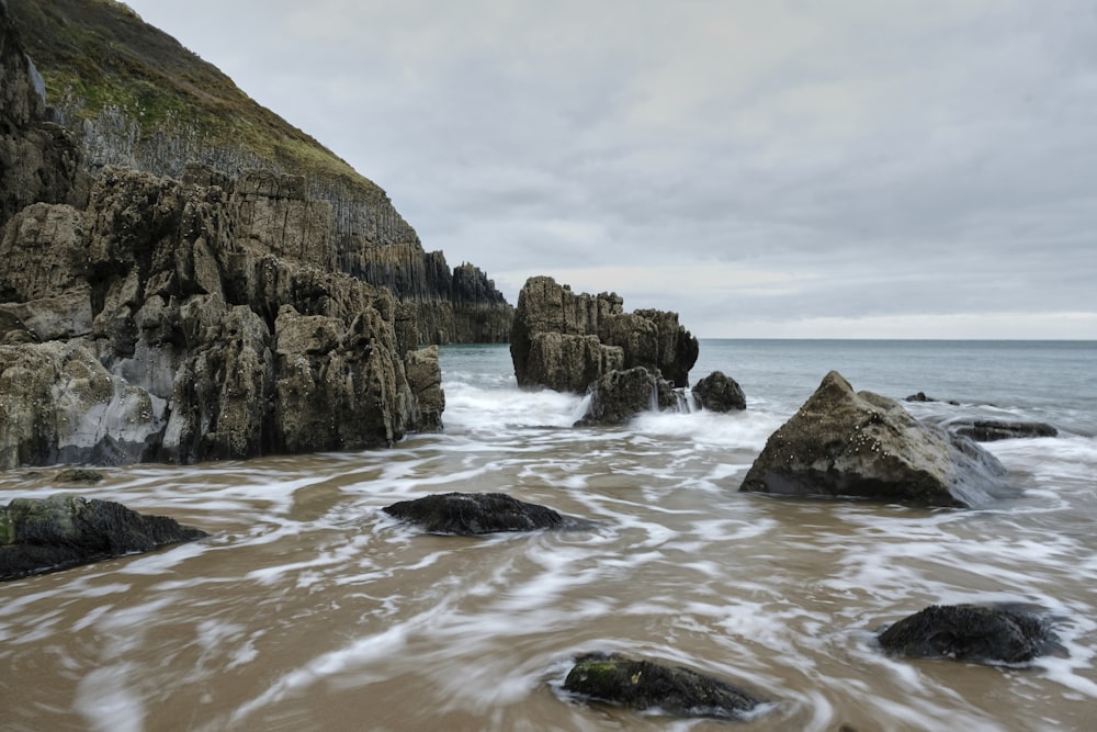 brown rock formation on sea water under white clouds during daytime