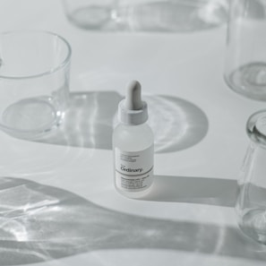 Minimalist serum bottles arranged on a white surface with lavender accents.