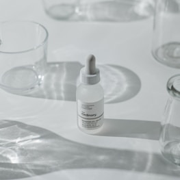 Minimalist flat lay of the Skin Tone Serum bottle surrounded by natural ingredients on a white background.
