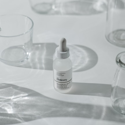 Minimalist skincare tubes and bottles on a smooth stone surface with subtle shadows.