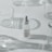 A minimalist arrangement featuring a dropper bottle of skincare product, surrounded by clear, empty glass containers casting soft shadows on a white surface.