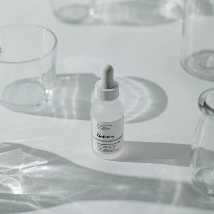 Minimalist flat lay of natural skincare bottles on a clean white surface with soft natural light