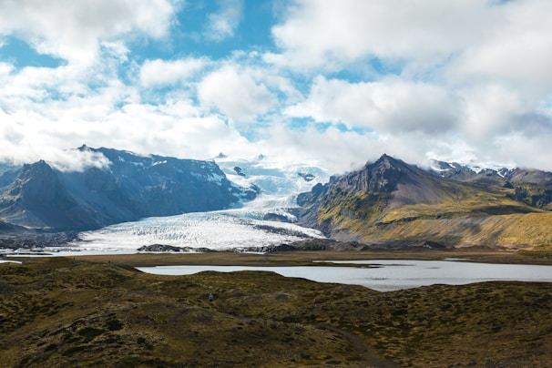 brown and green mountains under white clouds and blue sky during daytime