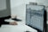 A person working at a desk with a computer monitor displaying a detailed technical drawing or architectural blueprint. The background is blurred, focusing on the screen with the design.