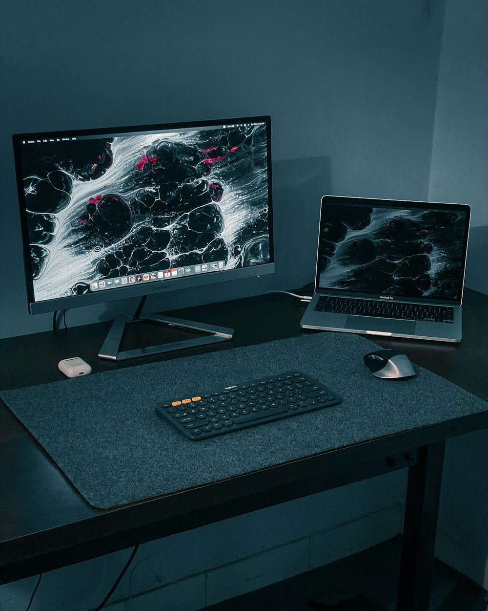monitor per computer a schermo piatto argentato e tastiera per computer nera su scrivania in legno nero
