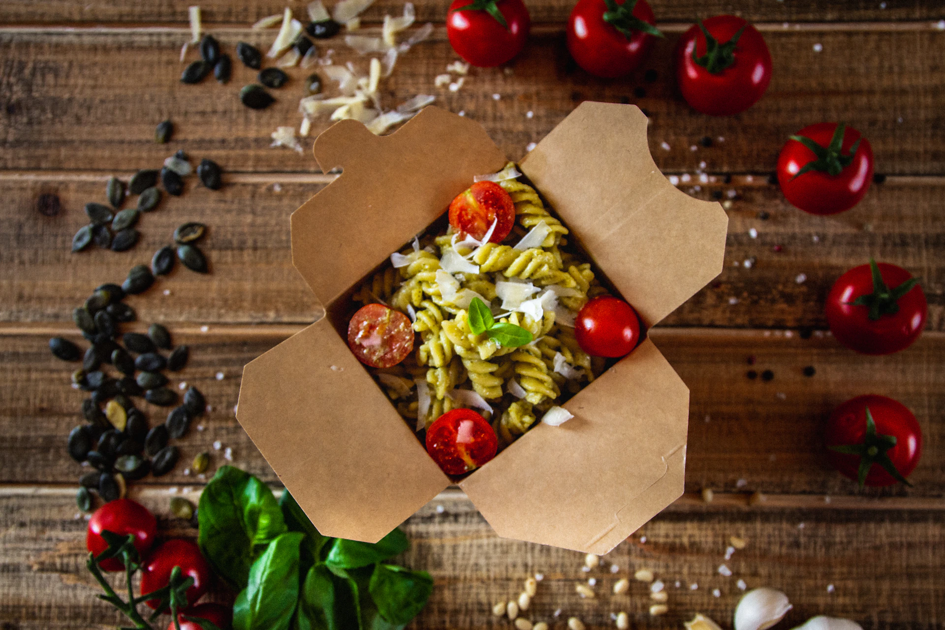 An overhead shot of a vibrant tomato basil penne pasta in a stylish black box, with golden accents catching the light, inviting you to dig in.