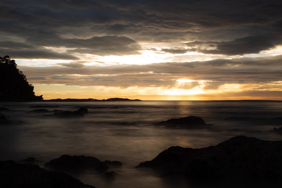 body of water under cloudy sky during sunset