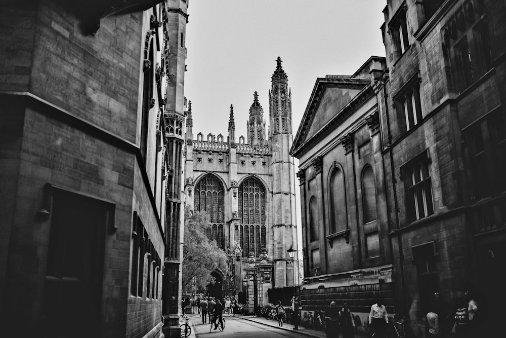 grayscale photo of people walking on street near building