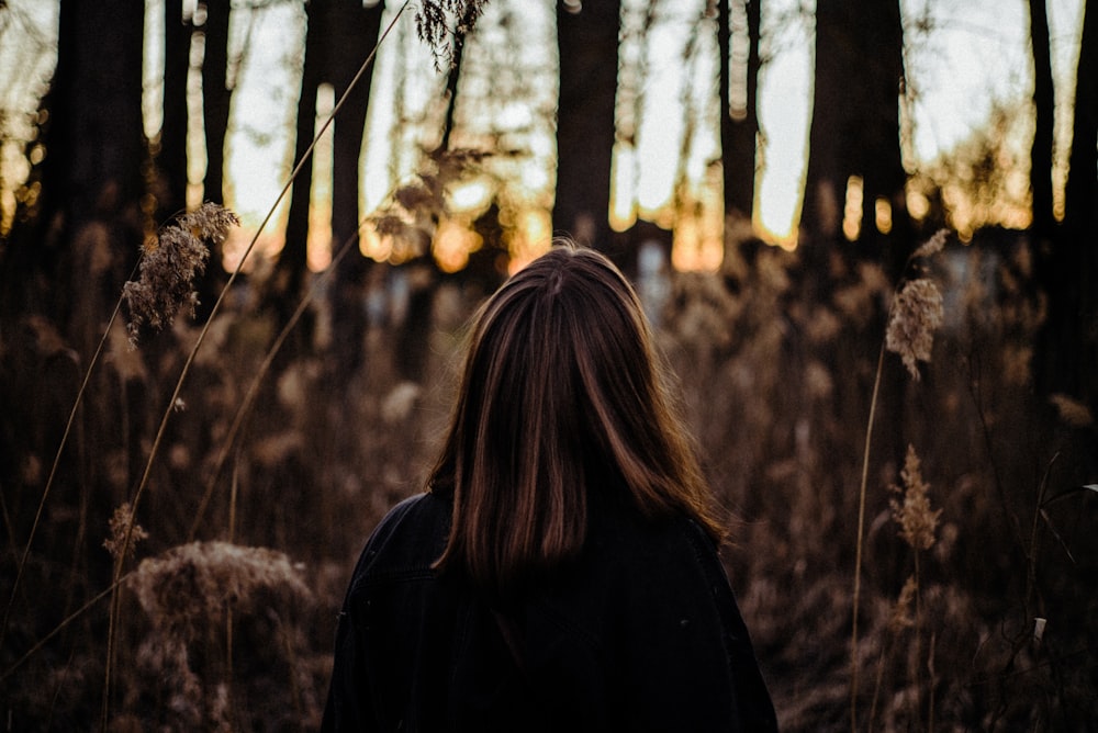 woman in black coat standing near trees during daytime