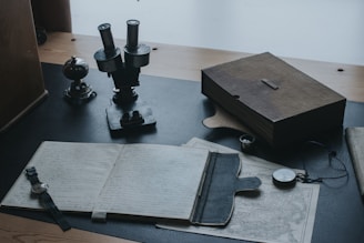 mesa de escritório, com cadernos, bússola, relógio e itens antigos de estudos