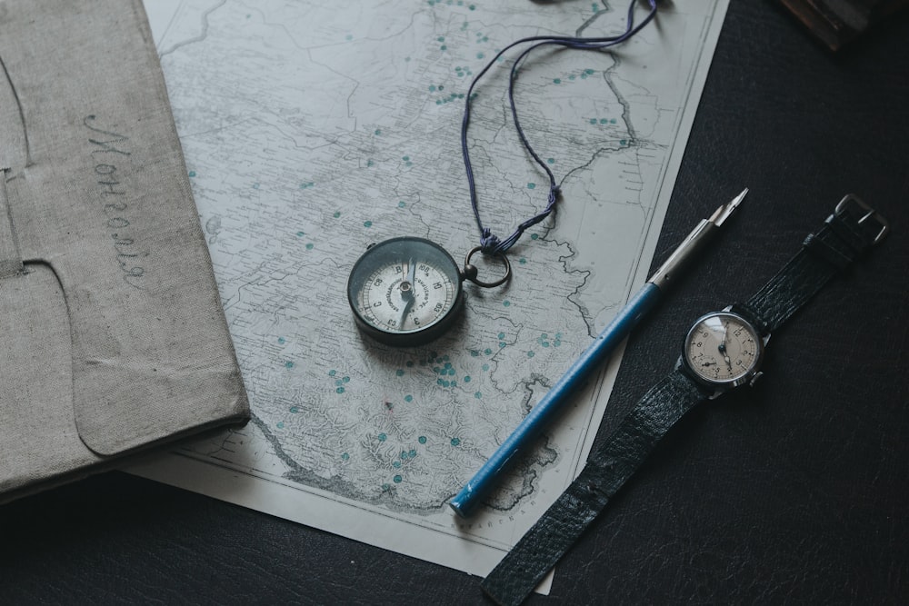 blue and white ballpoint pen beside silver round analog watch