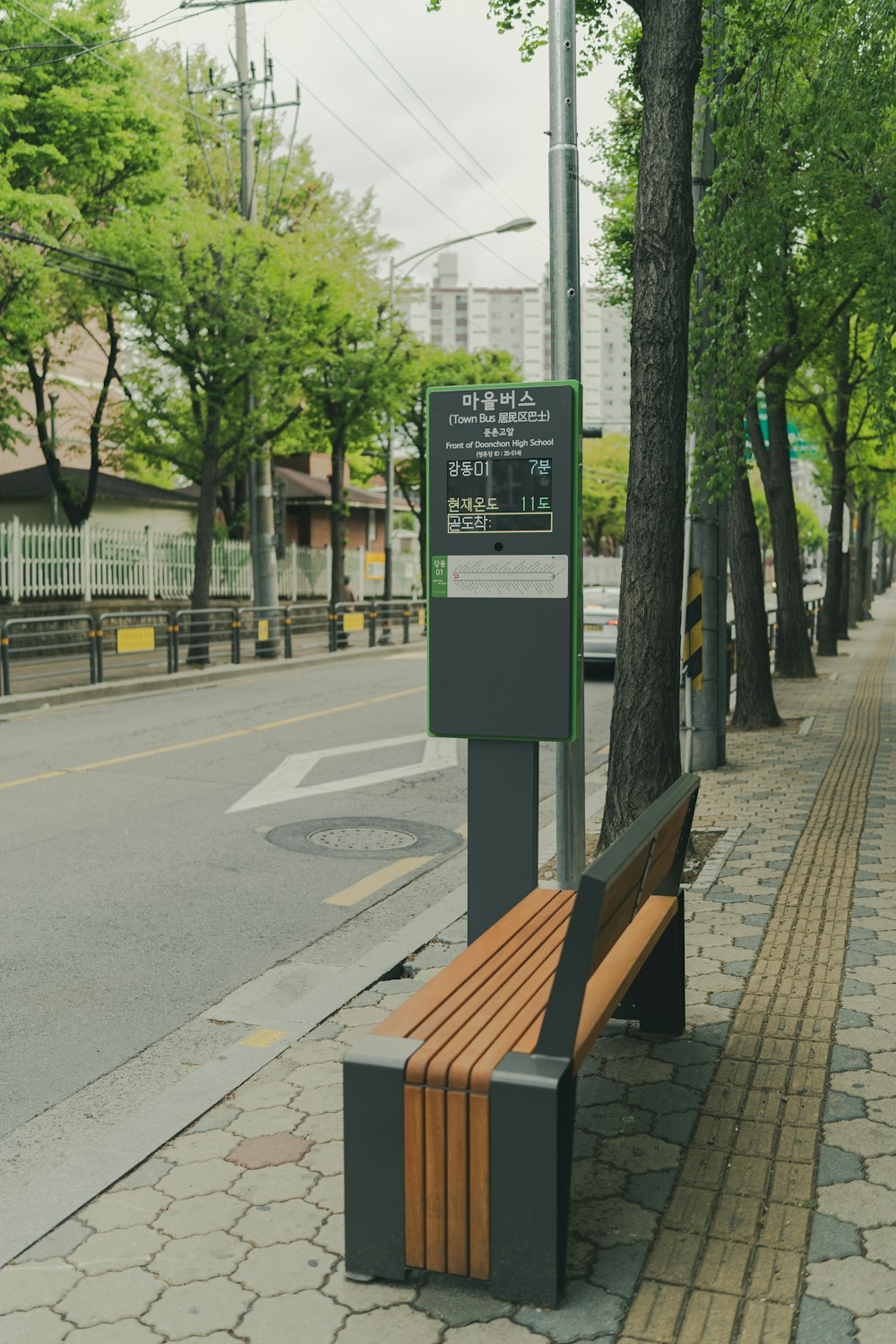 black and brown wooden bench near green trees and buildings during daytime