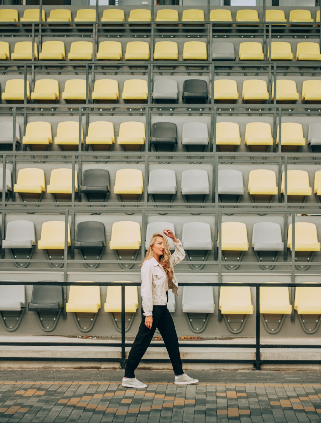 woman in white jacket and black pants standing on yellow and black stadium