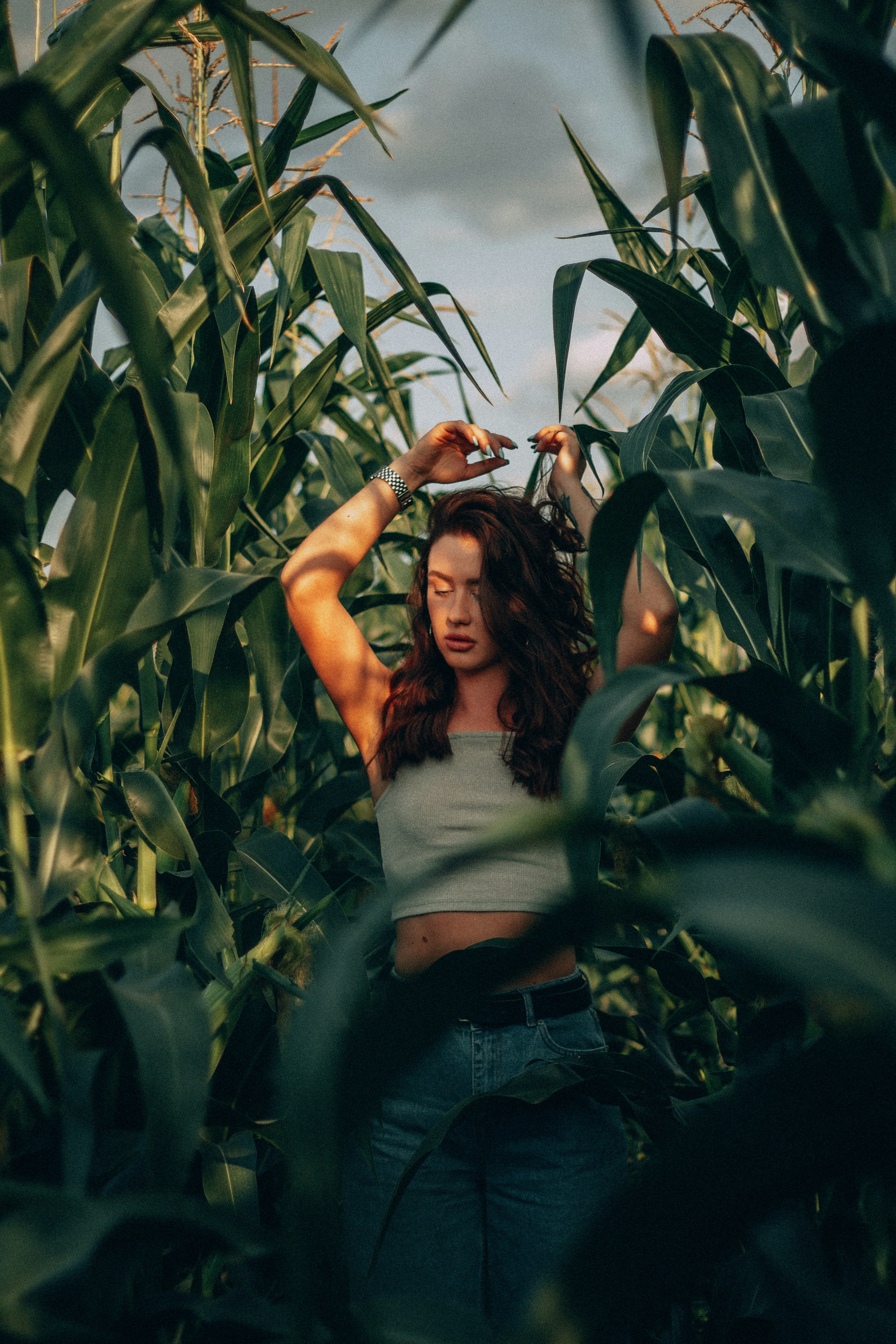 woman in white tank top standing on corn field during daytime