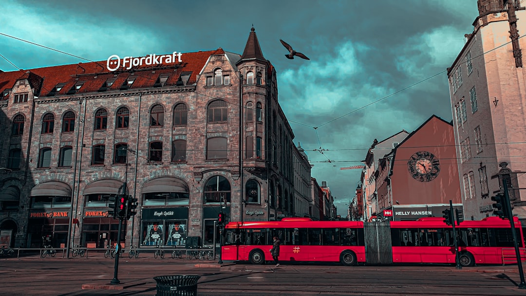 red double decker bus on road near brown concrete building during daytime