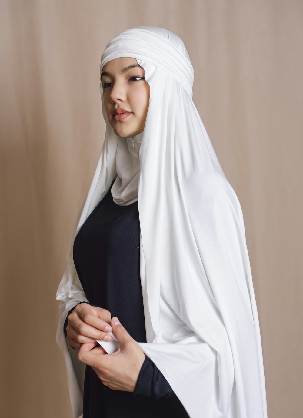 woman in white hijab standing near beige wall