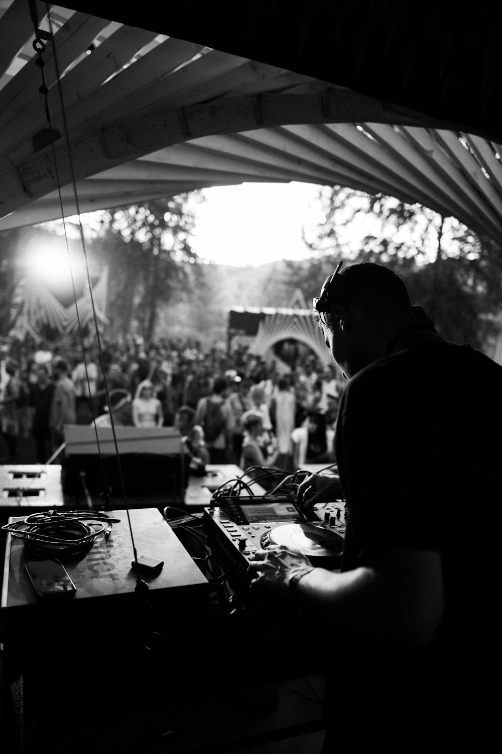 Foto en escala de grises de un hombre con camisa negra tocando el controlador de DJ