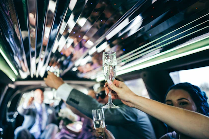 A friendly chauffeur opening the door of a limousine for a smiling couple on a special night out.