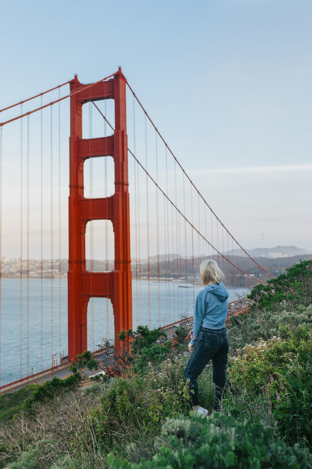 woman in blue jacket standing on the bridge during daytime