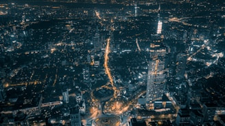 A nighttime aerial view of a city block illuminated with golden lights highlighting architectural details.