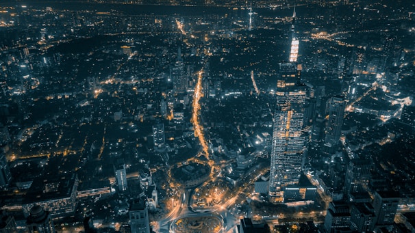 A nighttime aerial view of a city block illuminated with golden lights highlighting architectural details.